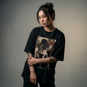 A young woman posing in a black t-shirt featuring a gothic anime style graphic.